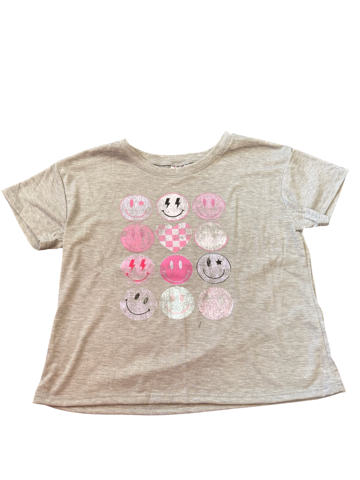A heather beige short-sleeve t-shirt featuring a grid of 12 circular smiley face graphics in various pink, white, and gray patterns across the chest.