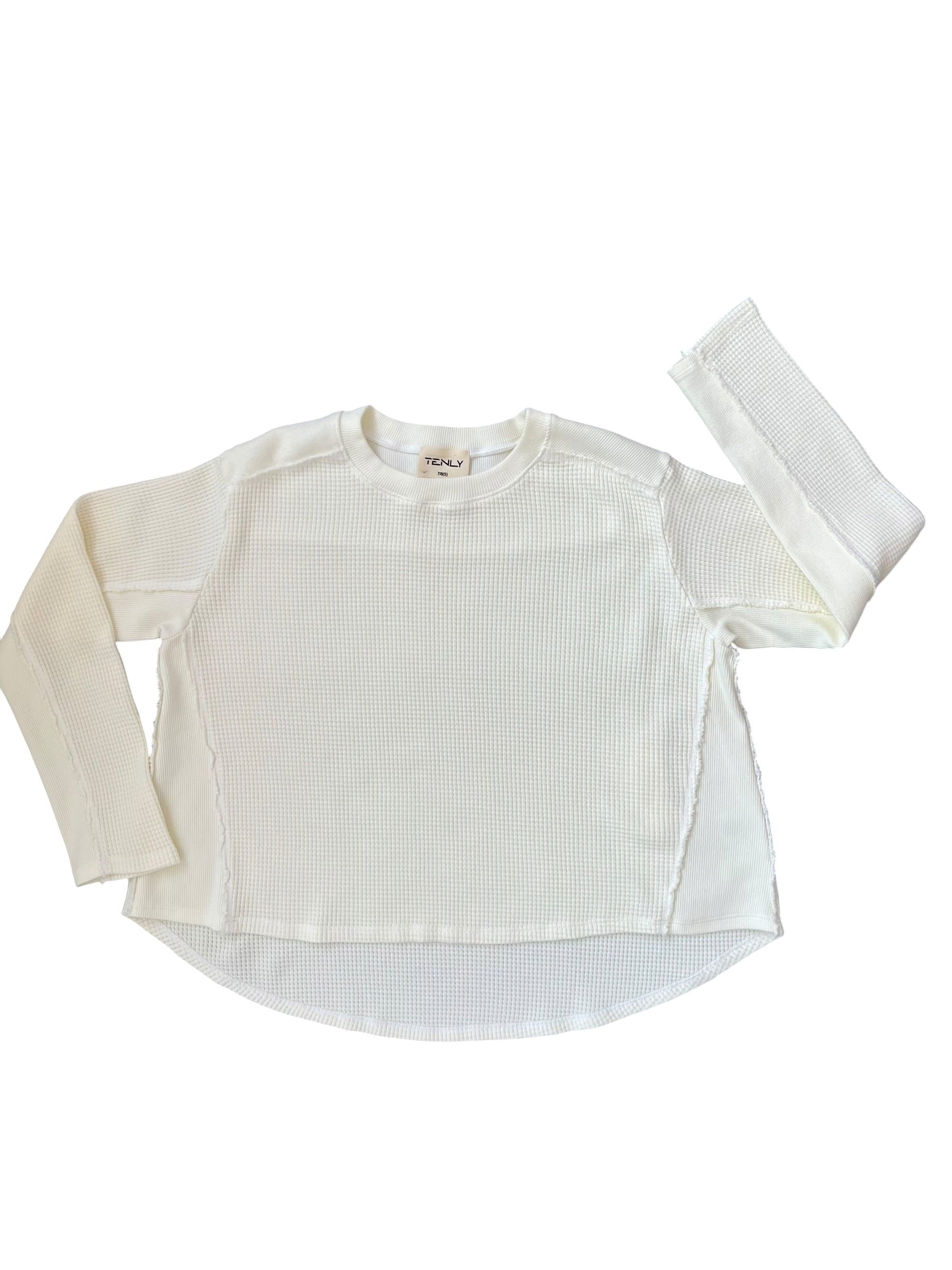 A long-sleeve waffled knit top in off-white, laid flat on a white background with one sleeve extended upward.