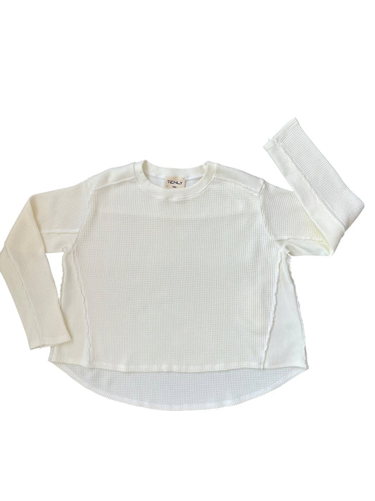 A long-sleeve waffled knit top in off-white, laid flat on a white background with one sleeve extended upward.